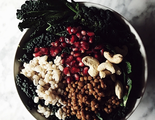 Un Buddha Bowl di cavolo nero, orzo, lenticchie e anacardi con una vinaigrette al melograno e miele.
